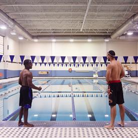 two male students standing at edge of pool fitness center